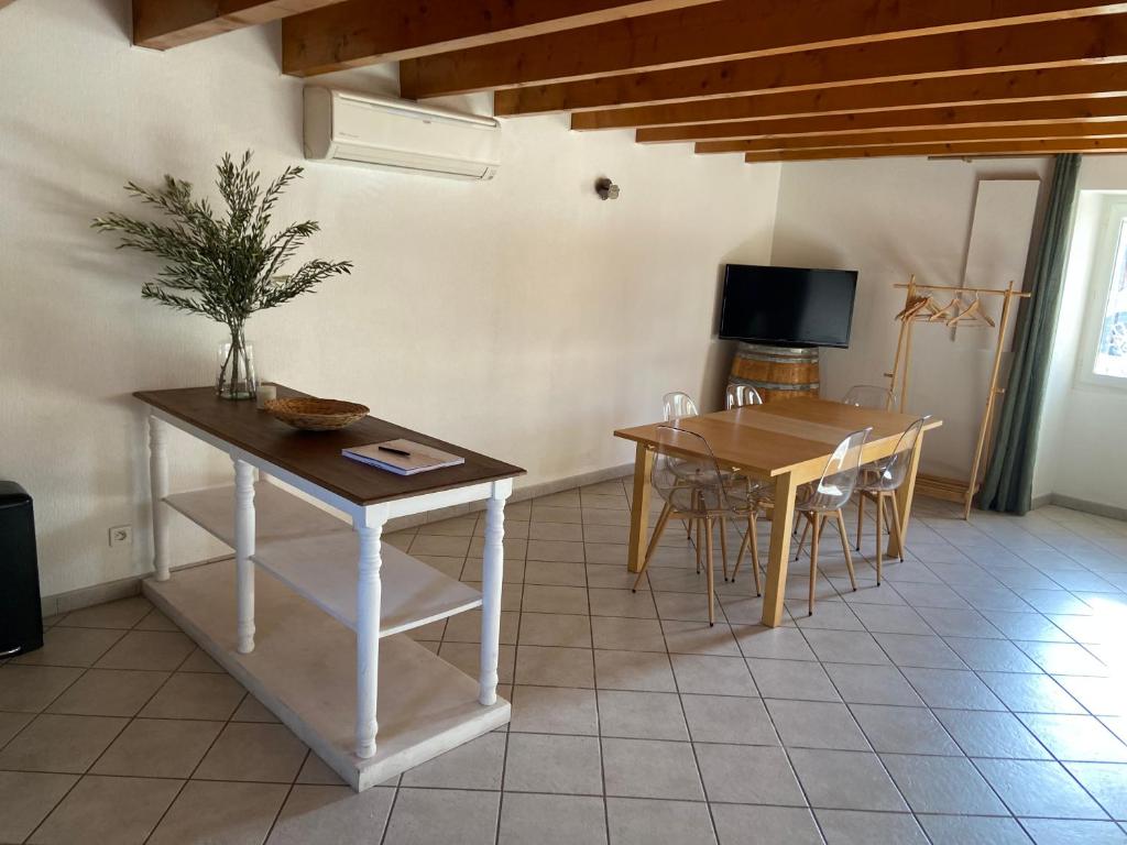 a living room with a table and chairs and a television at La maison des Petits Robins in Livron-sur-Drôme