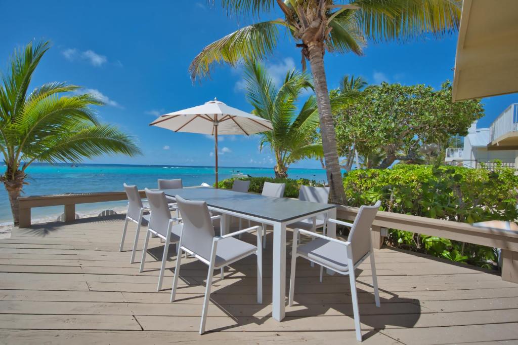 Incredible Beach Front Villa! في جورج تاون: طاولة مع كراسي ومظلة على الشاطئ