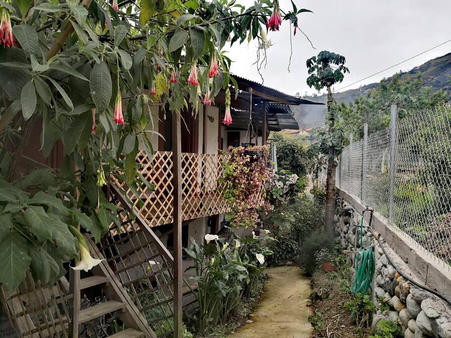 ein Haus mit einem Zaun und einem Garten mit Blumen in der Unterkunft Posada San Bartolomé in Sigsig