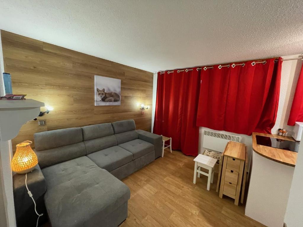 - un salon avec un canapé et un rideau rouge dans l'établissement Appartement Plagnes Villages, à La Plagne Tarentaise