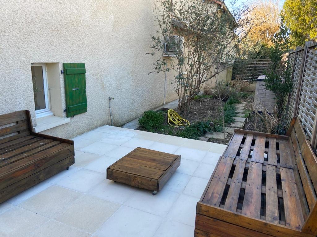 a patio with two wooden benches and a window at La maison des Petits Robins in Livron-sur-Drôme
