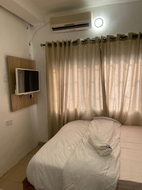 a bedroom with a bed and a window with a television at Mph mini in Lagos