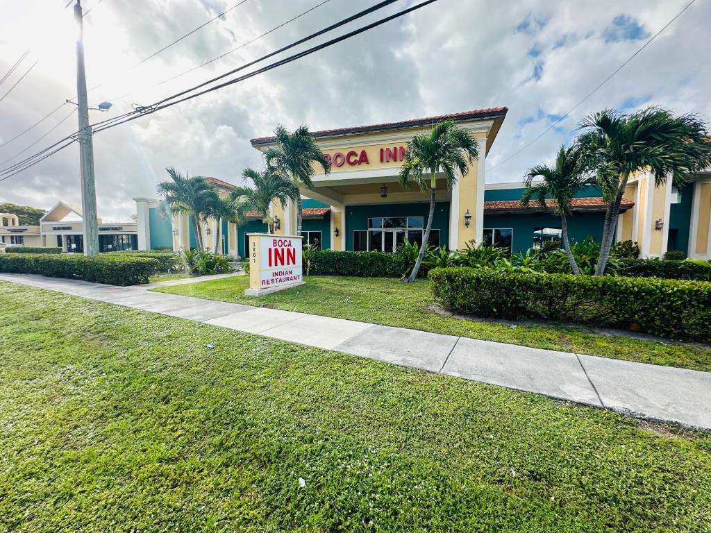 a sign in front of a building with palm trees at Boca Inn in Boca Raton