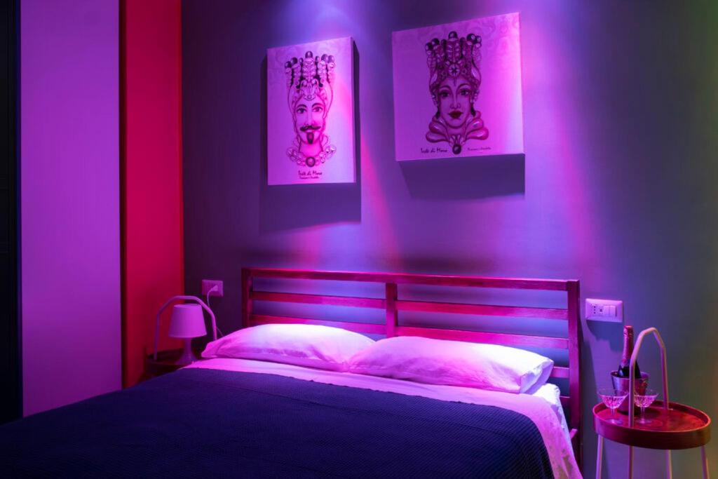 a bedroom with a bed with pink lights on it at Sicilia Bedda Taormina in Taormina