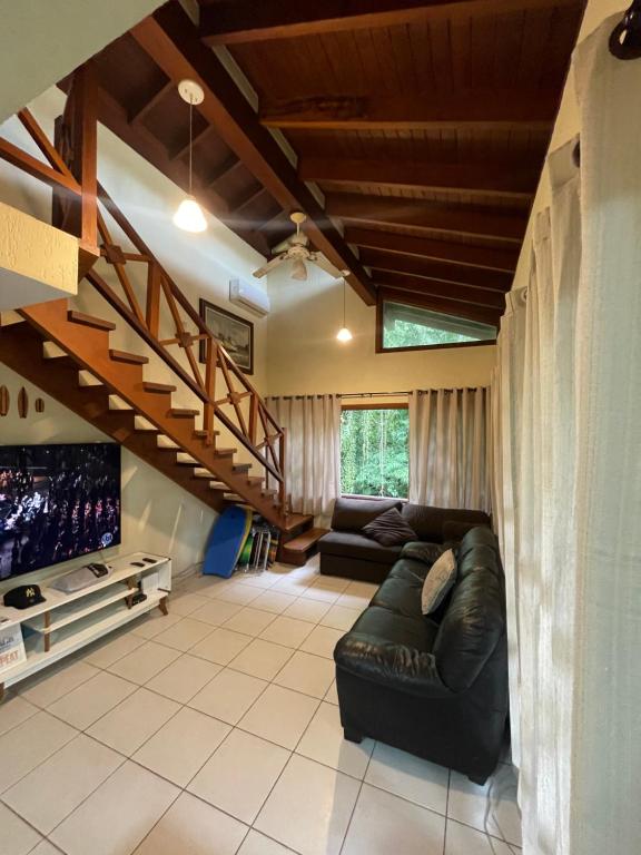 a living room with a black leather couch and a tv at B12 Casa em Maresias condomínio a 50 metros da praia in Maresias