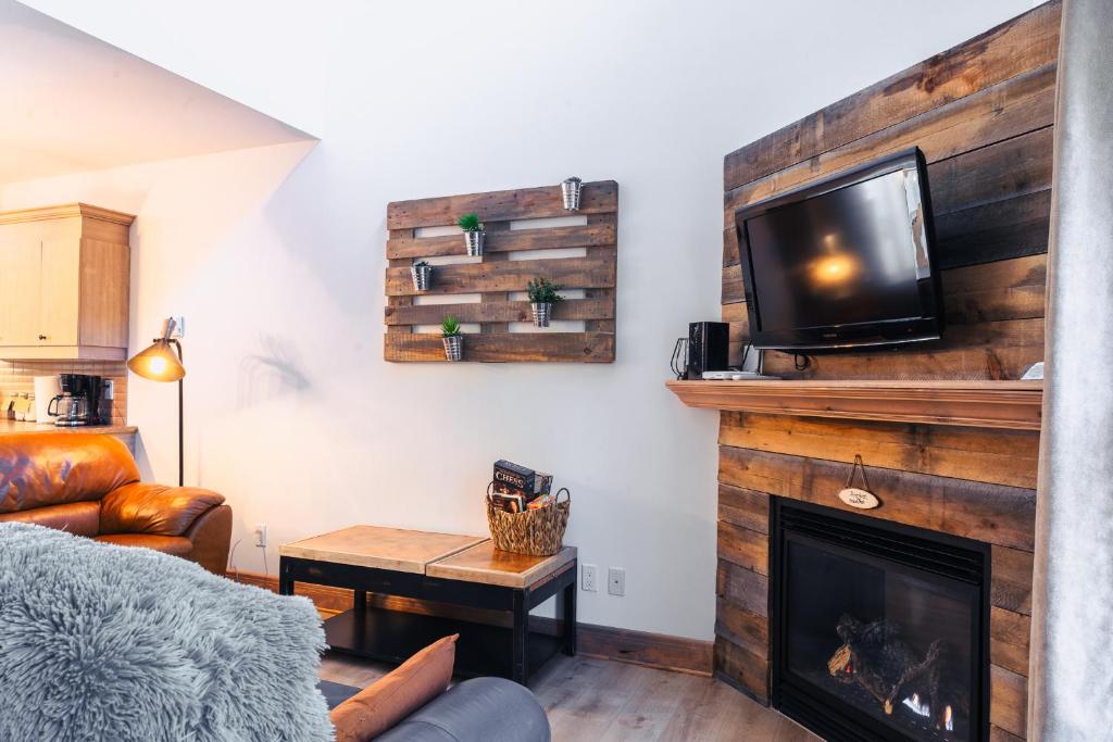 sala de estar con chimenea y TV en la pared en La petite saisonnière en Mont-Tremblant