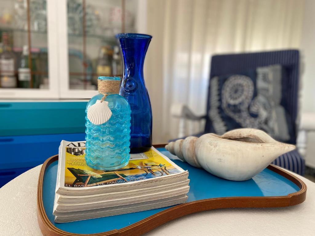 een tafel met een blauwe vaas en een stapel boeken bij Apartamento familiar a 200m de la playa in Alcossebre