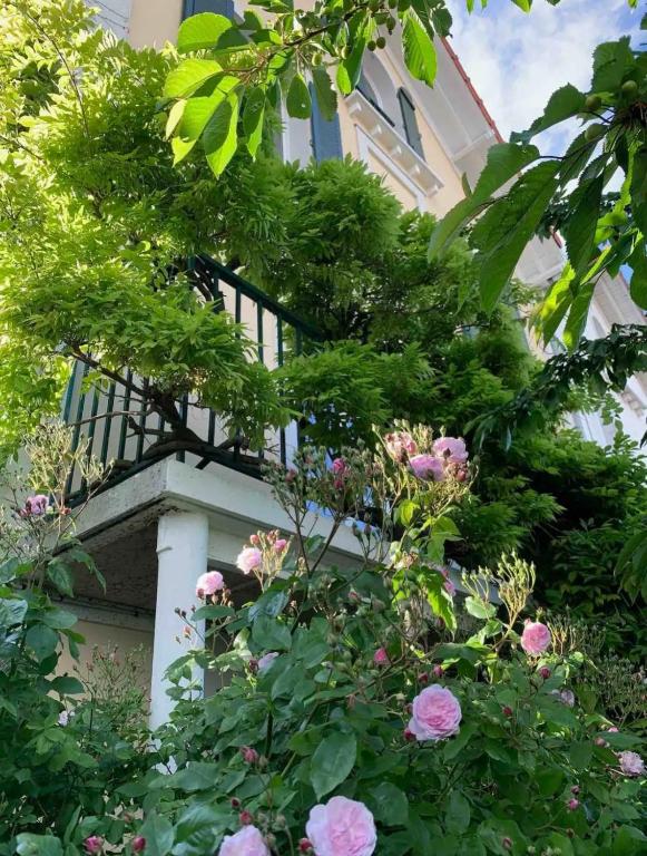 a garden with pink flowers in front of a building at Maison familiale avec vue tour Eiffel in Suresnes