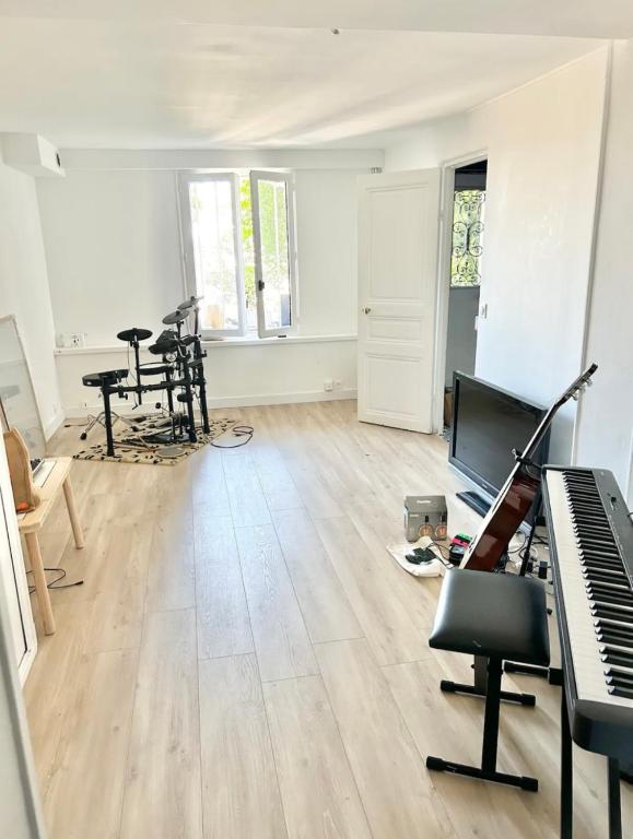 an empty living room with a piano and chairs at Maison familiale avec vue tour Eiffel in Suresnes