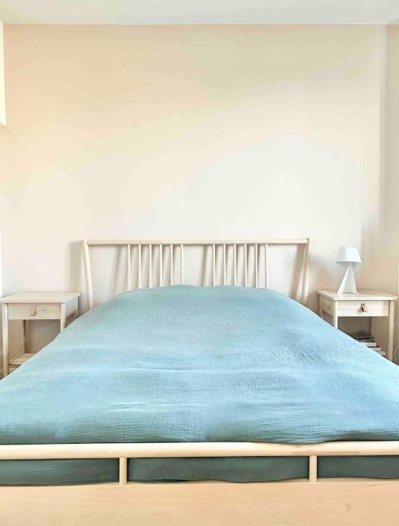 a bed with a blue blanket on top of it at Maison familiale avec vue tour Eiffel in Suresnes