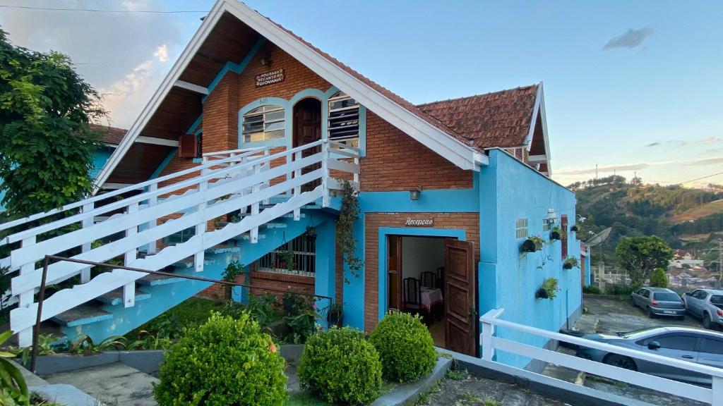 una casa azul con una barandilla blanca en Pousada Recanto da Giovana, en Campos do Jordão