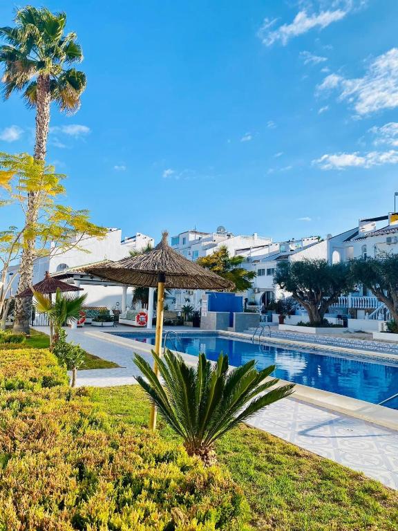 a resort with a swimming pool and a palm tree at CasasQuesada in Ciudad Quesada