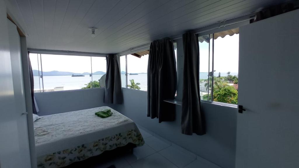 a bedroom with a bed and windows with a view at Pousada Alto da Maroca in São Francisco do Sul