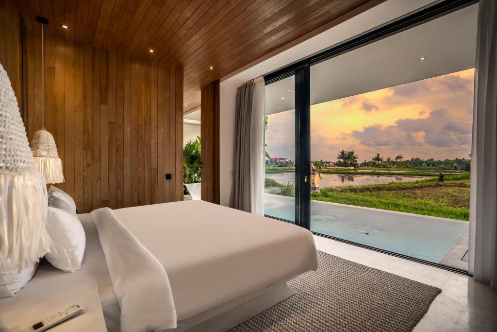 a bedroom with a bed and a view of a river at GREEN FlOW Villas Ubud II in Ubud