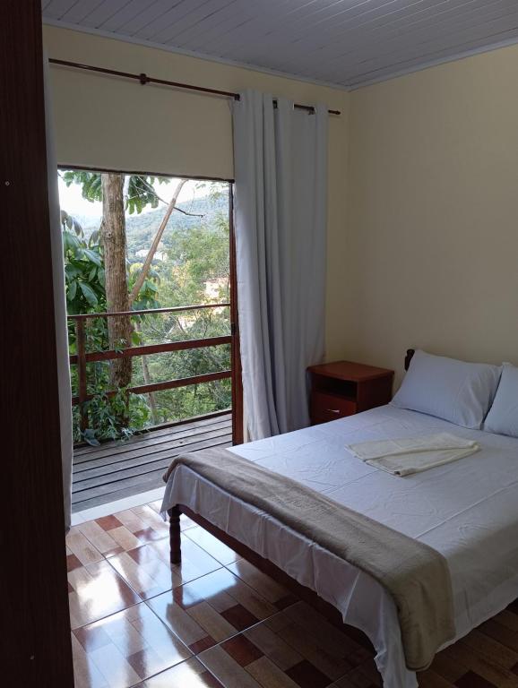 - une chambre avec un lit et une grande fenêtre dans l'établissement Flor da serra, à Santo Antônio do Pinhal