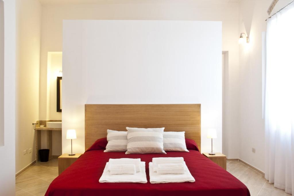 a bedroom with a large red bed with two white pillows at Nisí in Crotone