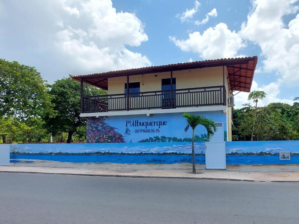 ein Gebäude mit einer Palme davor in der Unterkunft Pousada Albuquerque in Jijoca de Jericoacoara