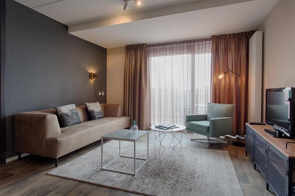 uma sala de estar com um sofá e uma televisão em Zuiderzeestate 35, prachtig appartement aan het IJsselmeer em Makkum