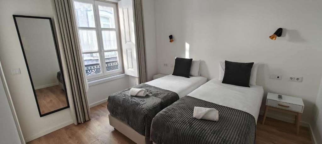 two beds in a room with a mirror and a window at Correio Velho Suites in Lisbon