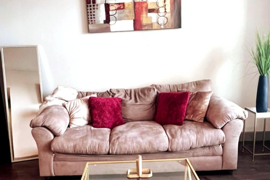 un sofá marrón con almohadas rojas en la sala de estar. en Comfortable Apartment in Dallas, en Addison