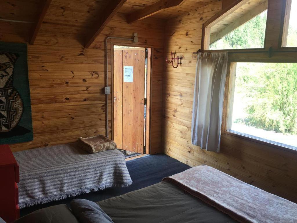 Habitación con cama y ventana en una cabaña de madera en Carelhue en Epuyén