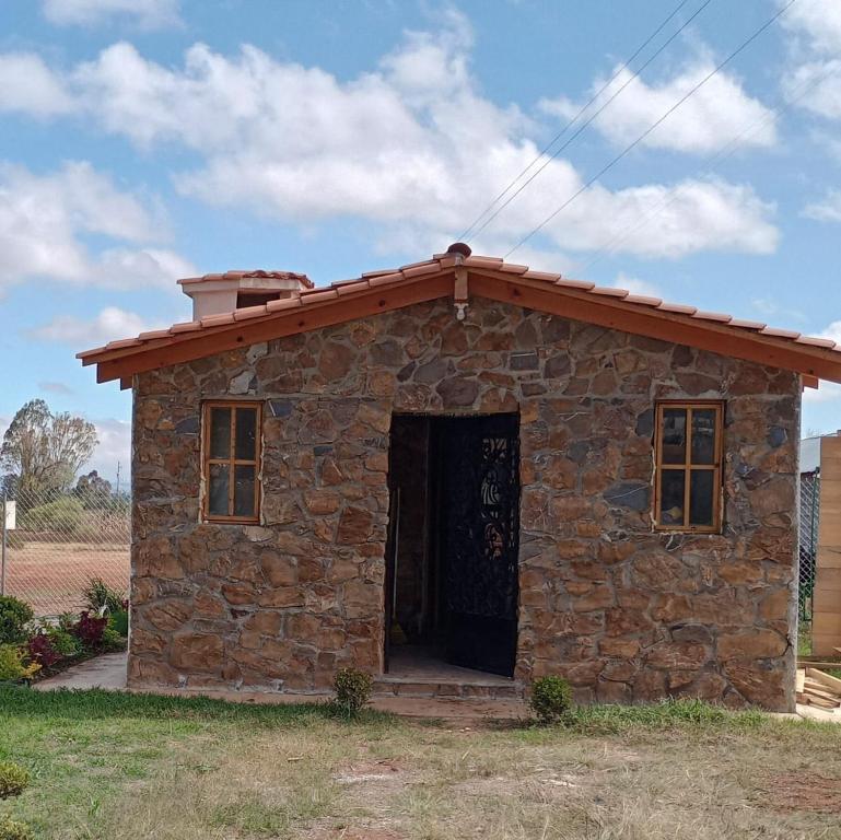 ein kleines Steingebäude mit rotem Dach in der Unterkunft Cabañas Angeles in Huasca de Ocampo