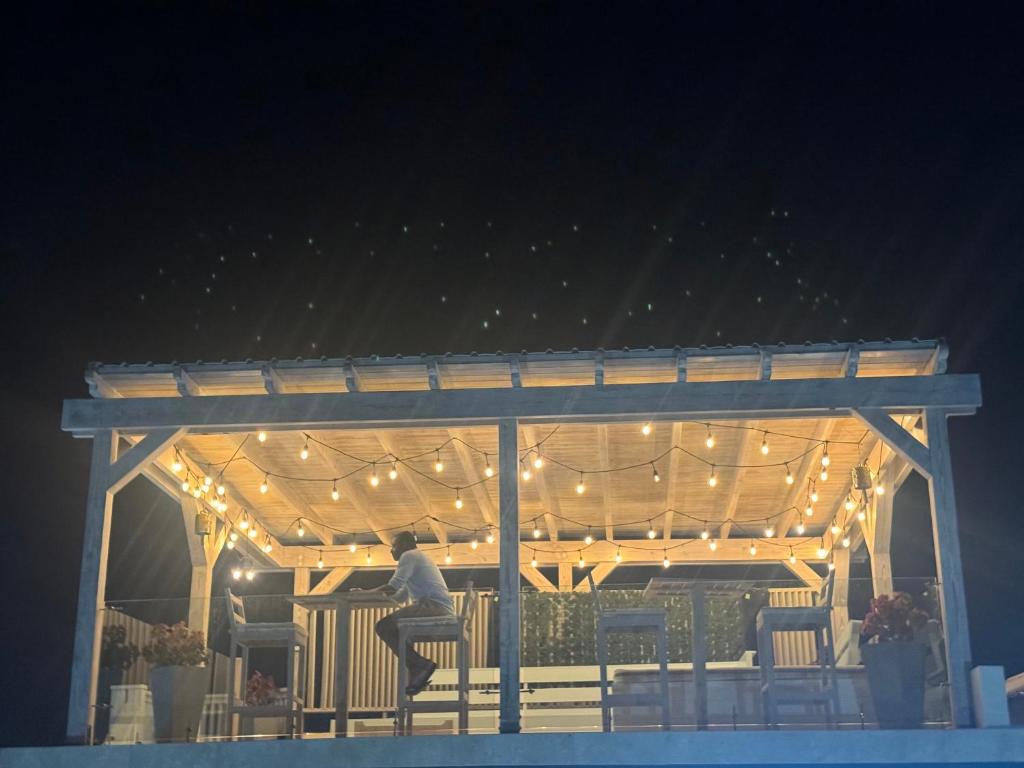 a person sitting on a pergola with lights on it at Seaside Escape in Wickhams