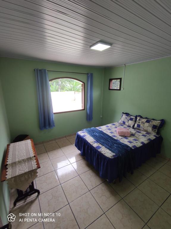 ein Schlafzimmer mit einem Bett in einem Zimmer mit einem Fenster in der Unterkunft Casa Muro Alto-Sana Rj in Macaé