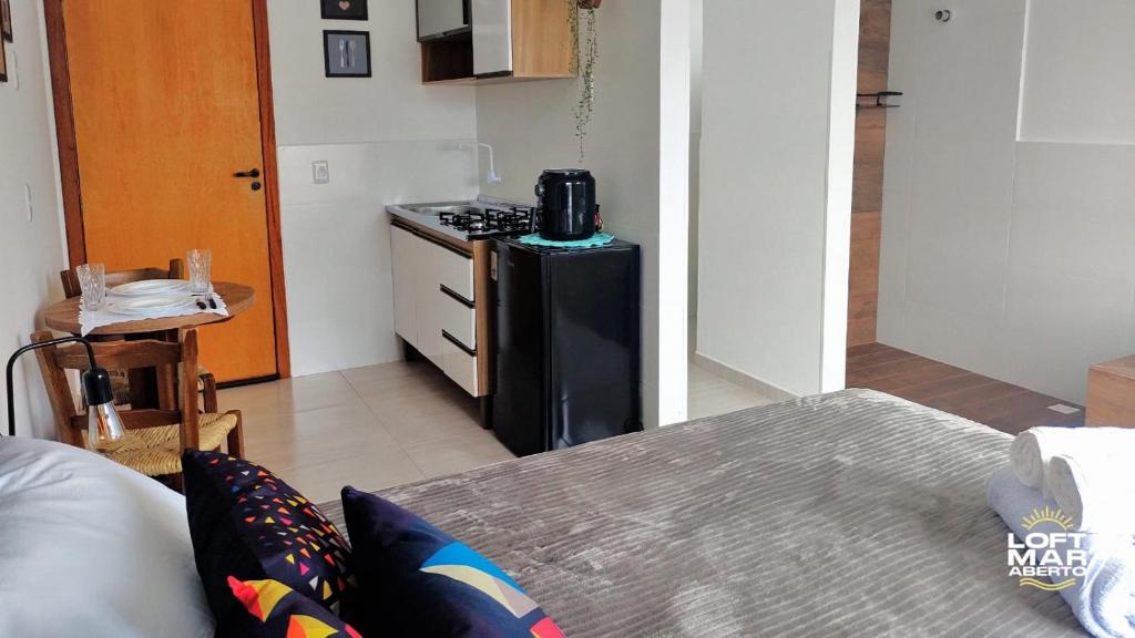 a kitchen with a stove and a refrigerator in a room at Charmoso Loft #1 próximo da praia com banheira in Pinheira
