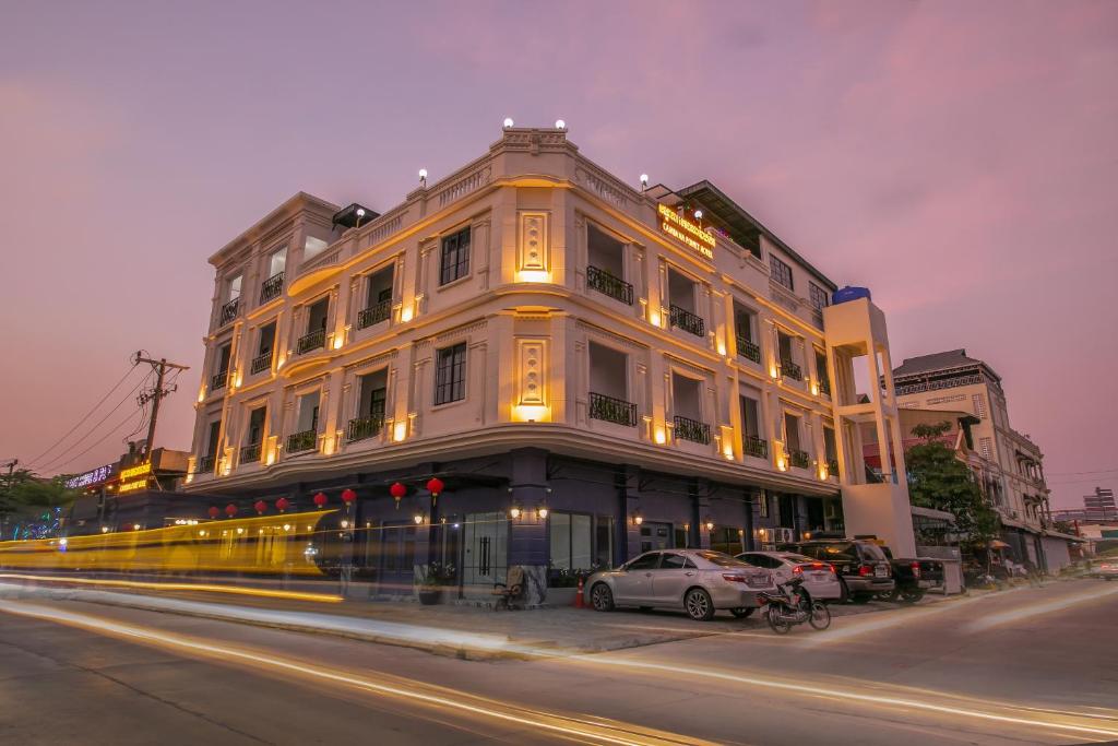 Cambana Poipet Hotel في بويبيت: مبنى ابيض كبير فيه سيارات تقف امامه