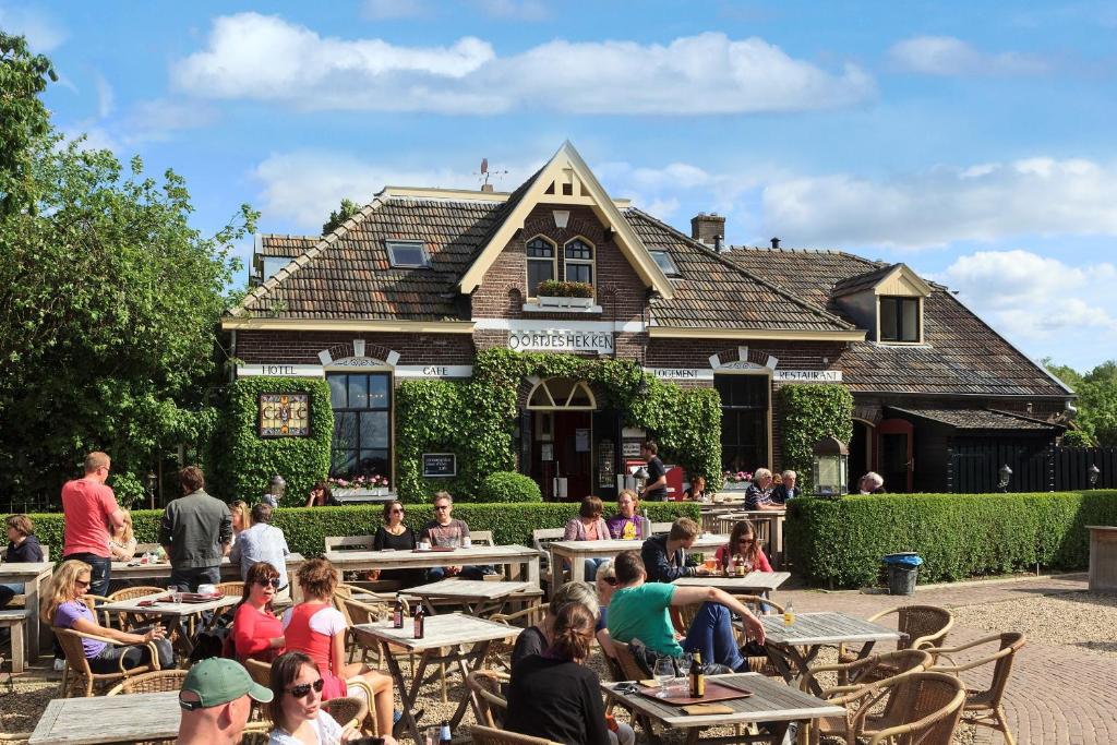 eine Gruppe von Personen, die vor einem Gebäude an Tischen sitzen in der Unterkunft Hotel Restaurant Oortjeshekken in Ooij