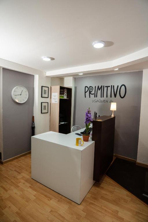 a room with a white table and a clock on a wall at Hotel Primitivo Usaquén in Bogotá