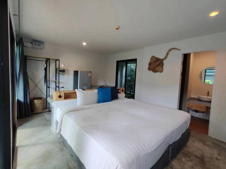 a bedroom with a large white bed in a room at KRAAM Silhouette Hotel & Cafe Phuket in Ban Kata