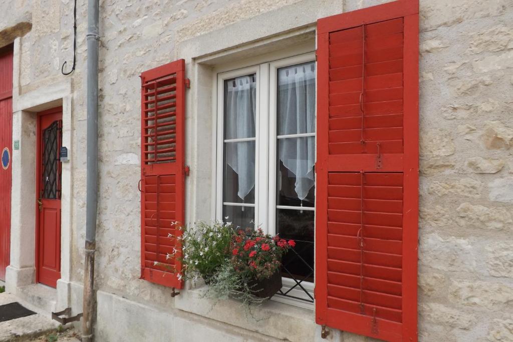 una ventana con persianas rojas en un edificio con flores en Gîte du Toilier, en Thillot-sous-les-Côtes