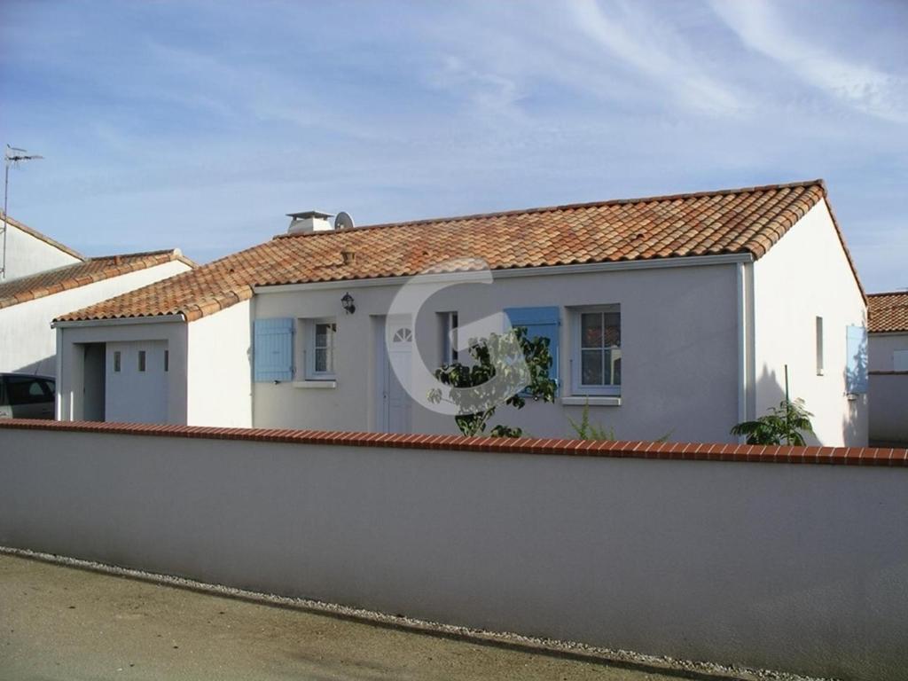 une maison blanche derrière une clôture dans l'établissement Maison cosy, 600m de la plage, tout confort, jardin clôturé, La Tranche-sur-Mer - FR-1-357-28, à La Tranche-sur-Mer