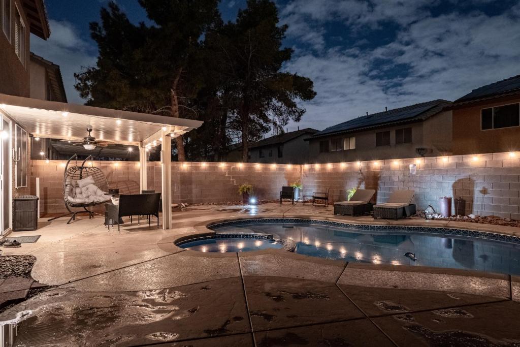 einen Hinterhof mit einem Pool und einer Terrasse mit Beleuchtung in der Unterkunft 5BR 3BA Family friendly entire home w pool, spa, games, tvs, and more in Las Vegas