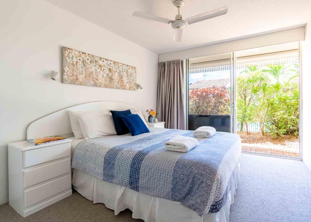 a bedroom with a bed with a blue blanket and a window at Secret Gem in Peregian Beach