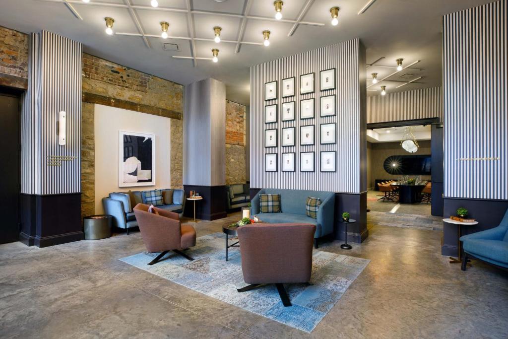 a lobby with couches chairs and tables in a building at Cyrus Hotel, Topeka, a Tribute Portfolio Hotel in Topeka