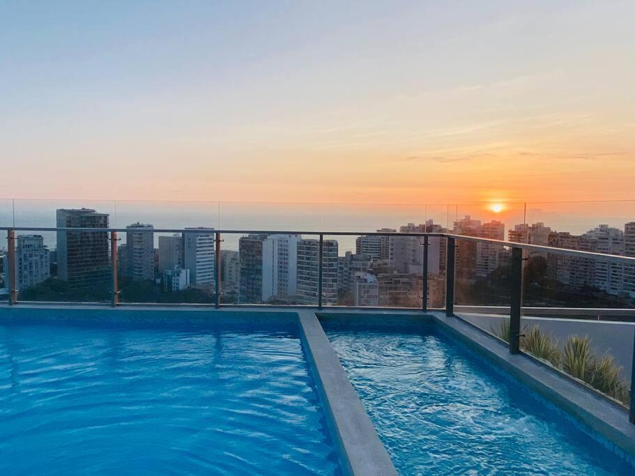una piscina en la parte superior de un edificio con puesta de sol en Barranco Aparment Luxury en Lima