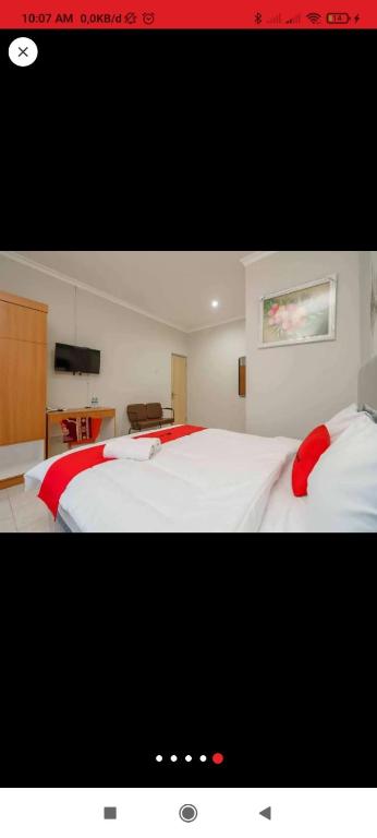 - une chambre avec 2 lits blancs et des draps rouges dans l'établissement Reddoorz near JIEXPO Kemayoran 2, à Jakarta