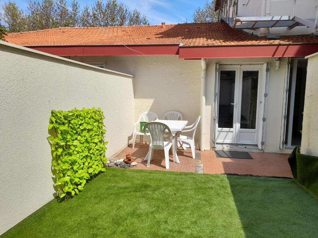 une terrasse avec une table et des chaises sur une pelouse dans l'établissement Appartement T2 à Arcachon près du centre et de la plage avec parking et terrasse - FR-1-319-465, à Arcachon