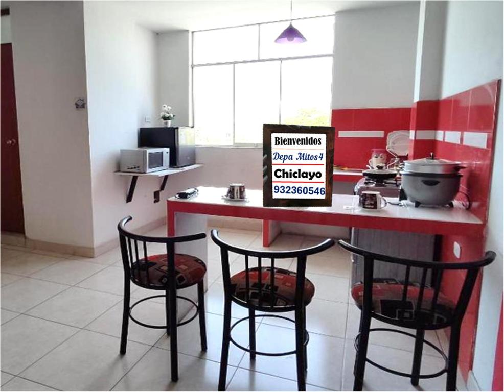 a kitchen with a counter with two chairs and a table with a sign at Departamento-Natural M4 in Chiclayo