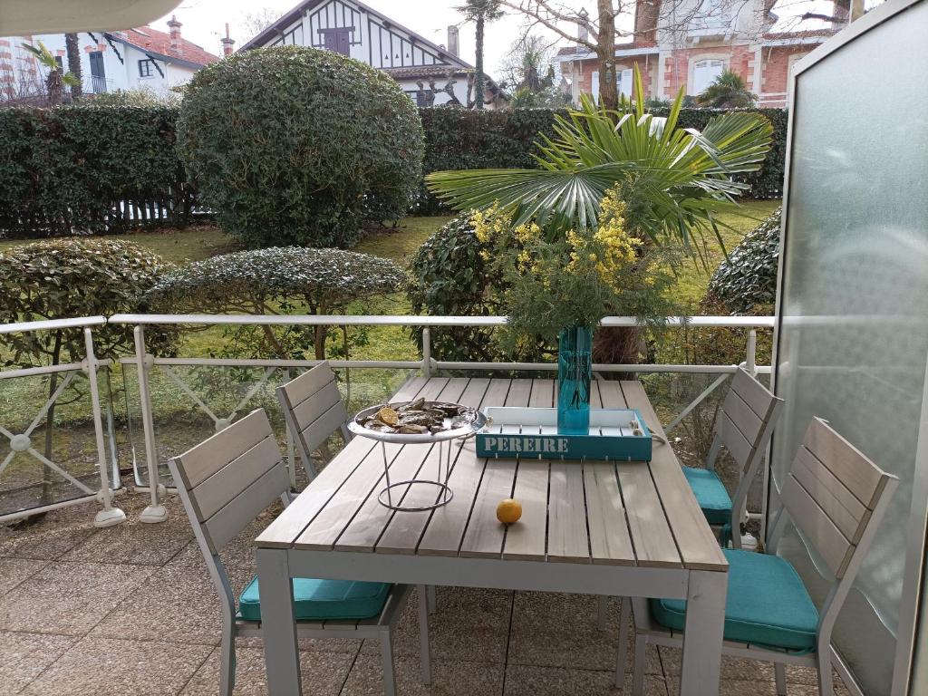 une table en bois avec des chaises et un vase. dans l'établissement Appartement T2 en Front de Mer à Arcachon, Accès Direct Plage, Parking, Animaux Admis - FR-1-374-201, à Arcachon
