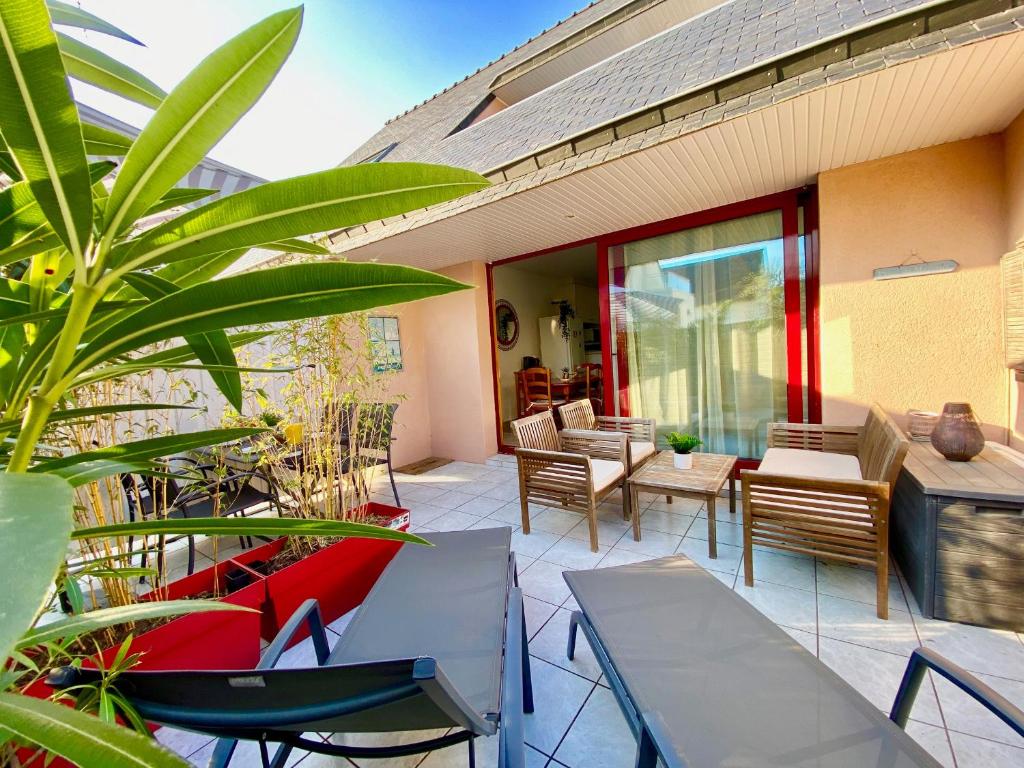 patio z krzesłami i stołami na balkonie w obiekcie Appartement calme à 3 min de la plage avec terrasse, parking et WIFI - FR-1-714-1 w mieście Clohars-Carnoët