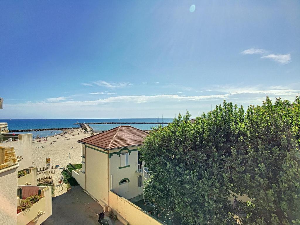 une maison sur la plage avec l'océan en arrière-plan dans l'établissement Location saisonnière - F3 - 8 pers - 1ère ligne - Garage - Animaux acceptés - FR-1-715-3, à Mauguio