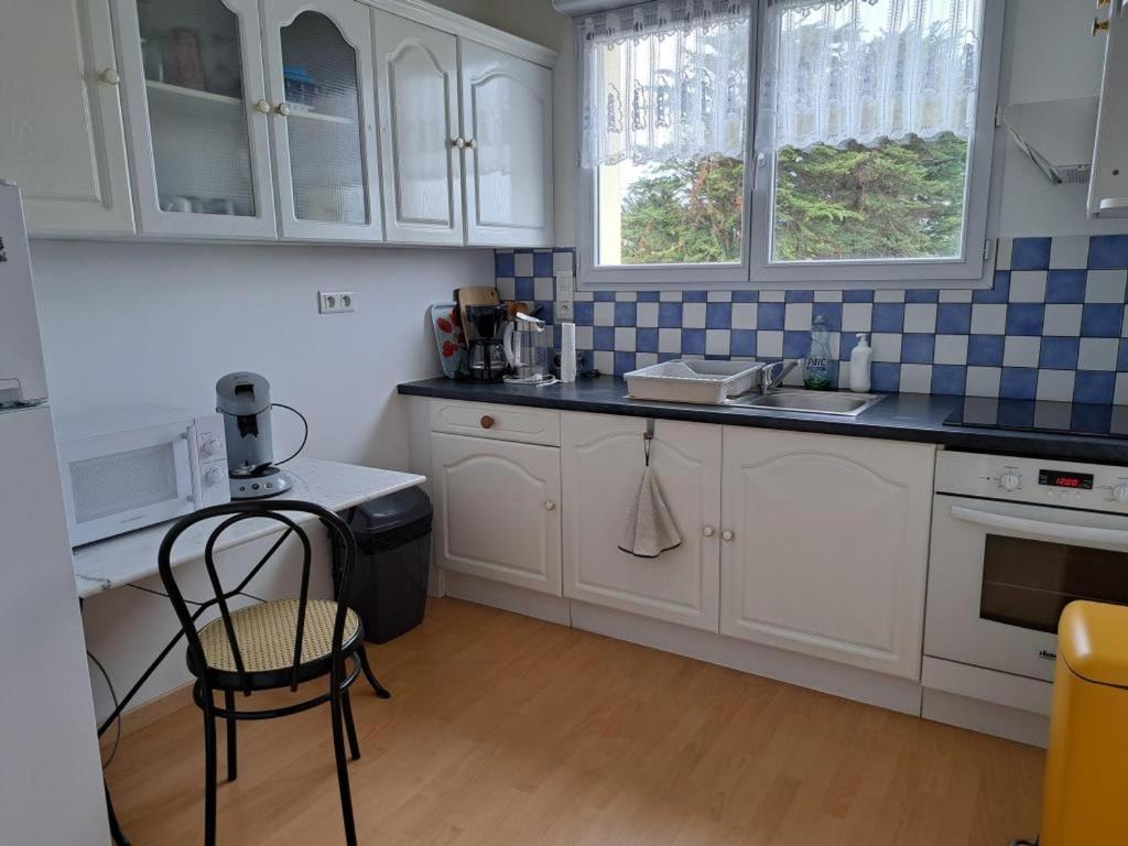 - une cuisine avec des placards blancs et une chaise dans l'établissement Appartement idéal quartier des Demoiselles : Plage, commerces, parking privé - FR-1-323-476, à Saint-Jean-de-Monts