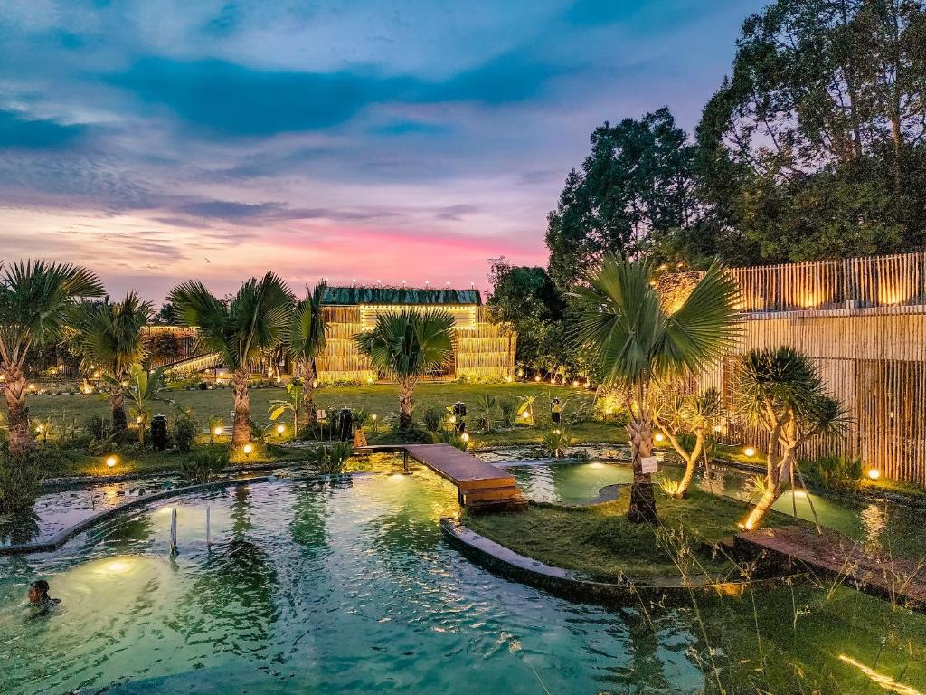 einen Pool in einem Park mit Palmen in der Nacht in der Unterkunft Tổ Boutique Garden in La Gi
