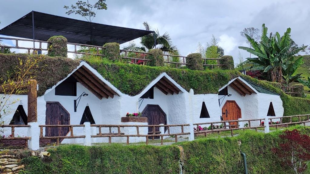 a house with a green roof on top of a hill at Hobbit Hotel Ecolodge- Guatapé in Guatapé
