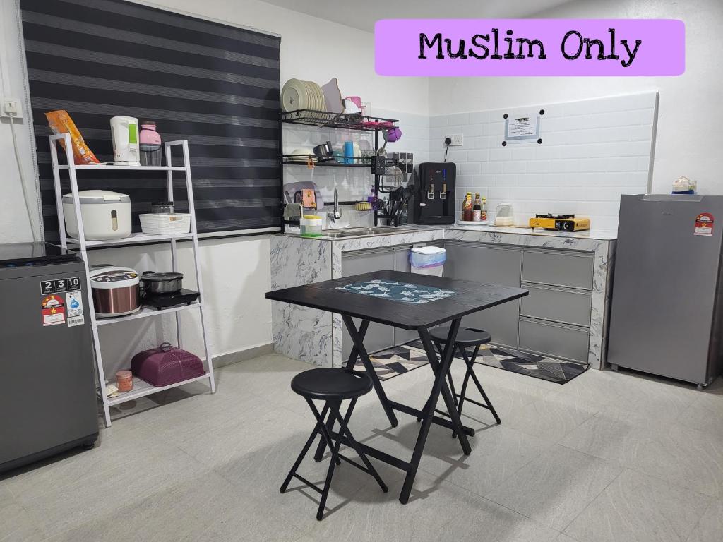 a kitchen with a table with two stools in it at Homestay Kasih Tok Ayah Sg Petani in Sungai Petani