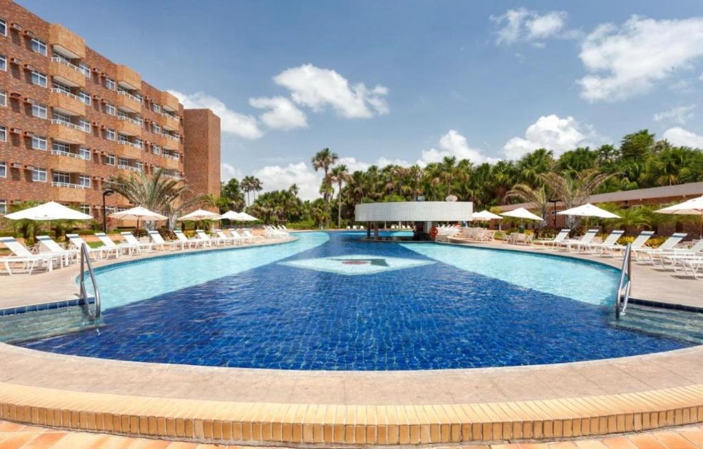 ein großer Pool mit Stühlen und Sonnenschirmen in der Unterkunft Hotel - Gran Lençóis flat 410 in Barreirinhas